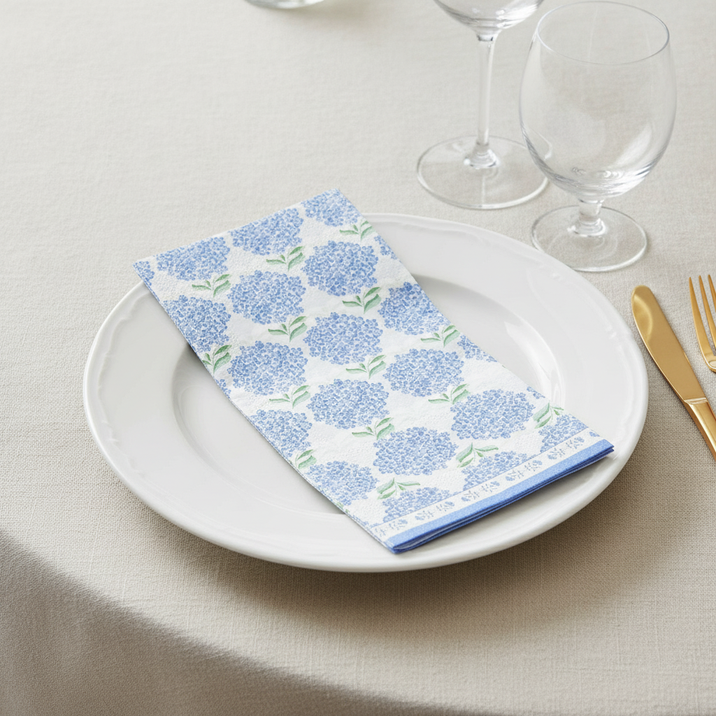 Hydrangea floral paper napkin folded on a white plate place setting with gold cutlery