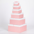 Set of six pink square nesting gift boxes with white lids and ribbon