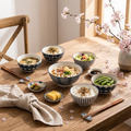 Hefeng floral porcelain bowl set styled on a dining table with chopsticks and cherry blossom sprigs