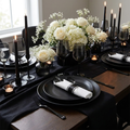 Black pre-rolled plastic cutlery set in an elegant dark moody dinner party tablescape with black plates and candlelight