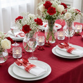 Red pre-rolled plastic cutlery set on an elegant festive table setting with white plates and red linen florals