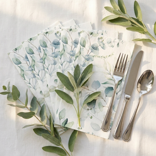 Sage eucalyptus napkins fanned with fresh eucalyptus sprigs and silver cutlery on white linen