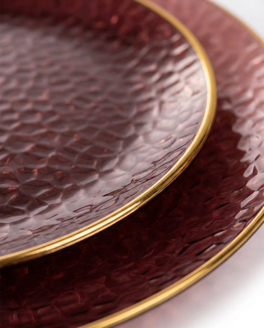 Close-up of burgundy hammered plastic plate showing gold rim texture and elegant detail