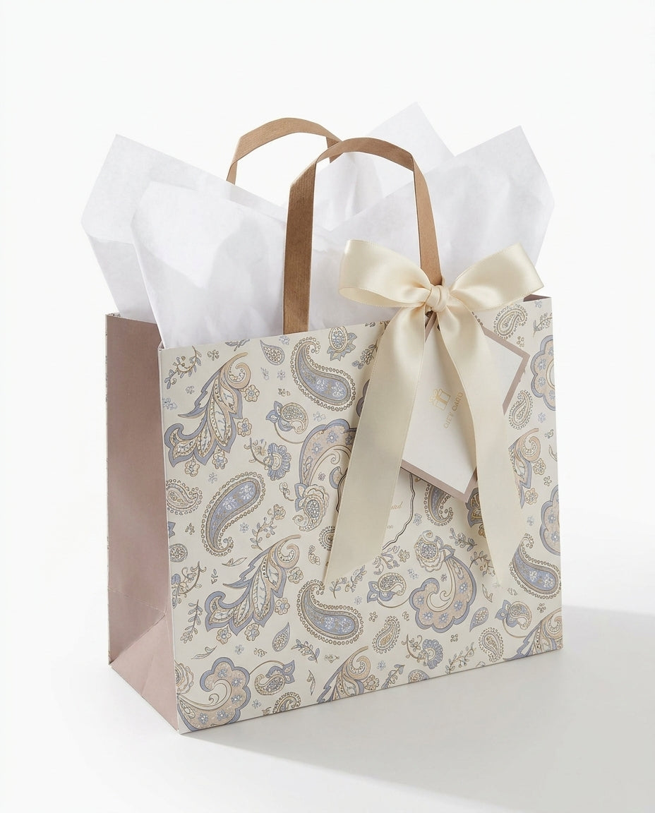 Sophia botanical-print kraft gift bag standing upright stuffed with white tissue paper, gift card and satin ribbon tied around handle
