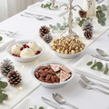 Silver snowflake paper bowls styled in an elegant winter holiday table setting with ice cream, pinecones and fairy lights
