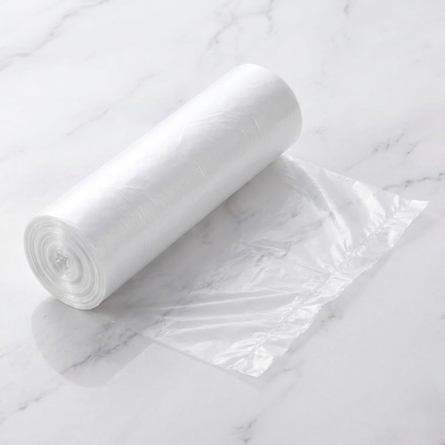 Roll of clear perforated 4-gallon trash bags with one bag held open on white marble